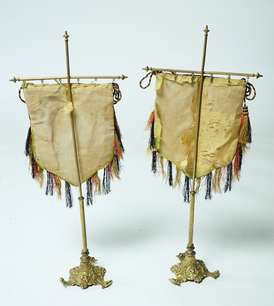 A pair of 19th century cast brass table screens, with floral Berlin Bead worked banners. 54cm high. Condition - the fringing has worn in places, silk backing has torn, both could be removed.